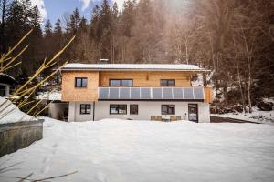 une maison avec un panneau solaire dans la neige dans l'établissement Caroline's Appartement, à Au im Bregenzerwald