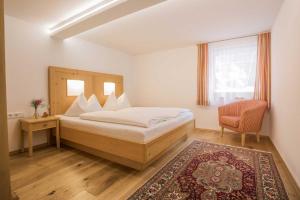 um quarto com uma cama, uma cadeira e uma janela em Caroline's Appartement em Au im Bregenzerwald