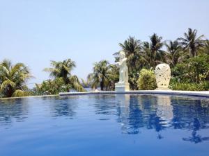 a swimming pool with a statue in front of trees at Toyabali Resort, Dive & Relax in Tulamben
