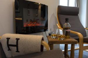 a living room with a table with two glasses and a bottle of alcohol at Cairn Leuchan in Ballater