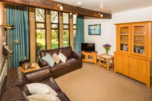 a living room with a leather couch and a television at Ratty's Retreat in Blockley