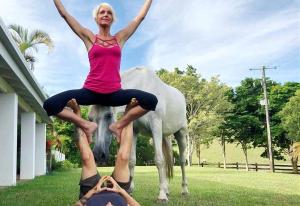 a woman standing on the back of a man in front of a horse at Eumundi Mountain Retreat in Eumundi