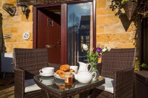 a table with a tea pot and a vase on it at Ratty's Retreat in Blockley