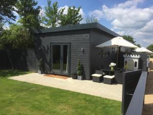 un petit hangar noir avec une table et un parasol dans l'établissement Willow Court Farm Studio West & Petting Farm, 8 mins to Legoland & Windsor, 15 mins to Lapland UK, à Windsor