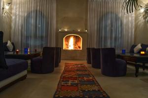 a living room with a fireplace with chairs and a rug at Lina Ryad & Spa in Chefchaouene