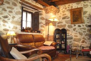 sala de estar con sofá de cuero y paredes de piedra. en Casa Doña Ligia, en Mijares