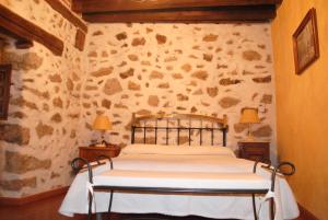 1 dormitorio con 1 cama en una pared de piedra en Casa Doña Ligia, en Mijares