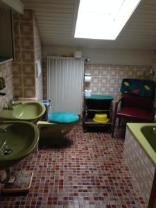 een badkamer met 2 groene wastafels en een rode stoel bij Gästehaus Färbinger in Bayerisch Gmain