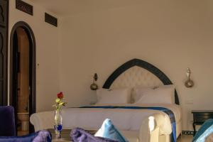 a bedroom with a white bed with a vase of flowers on a table at Lina Ryad & Spa in Chefchaouene