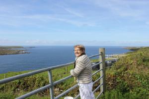Un uomo in piedi vicino a una recinzione vicino all'oceano di Clifden Bay Lodge a Clifden