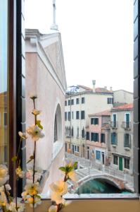a view of a bridge from a window with flowers at Ca' dell' Artista with Balcony and Terrace in Venice