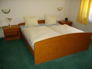 a bedroom with a wooden bed with two night stands at Hotel Kraichgauidylle in Malsch