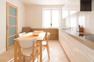 een keuken met een houten tafel en witte stoelen bij Duplex in De Panne