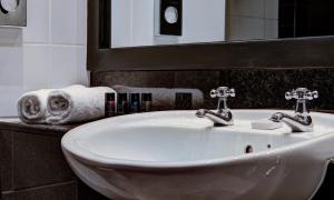 a bathroom sink with two faucets and a mirror at House Belfast Hotel in Belfast