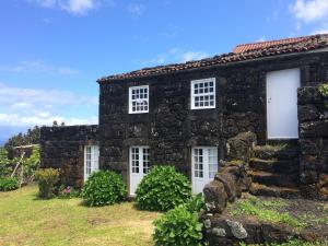 an old stone house with white doors and windows at Casa Da Lava in São Roque do Pico