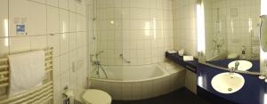 a bathroom with a tub and a toilet and a sink at Hotel Ascot Bristol in Potsdam +16 photos