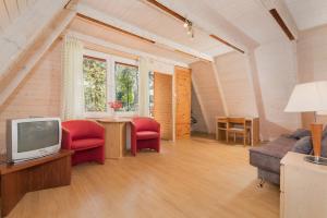 a living room with a tv and red chairs at Gryf Domki Pobierowo in Pobierowo