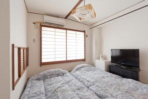 Shin Okubo Sekitei في طوكيو: غرفة نوم بسرير وتلفزيون بشاشة مسطحة