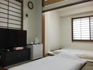 东京新大久保石亭酒店的一间卧室，配有两张床和一台平板电视