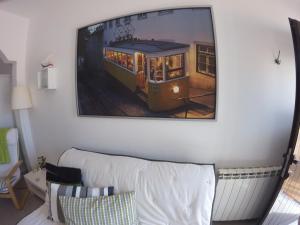 a painting of a trolley car hanging on a wall at Stella's House in Nazaré