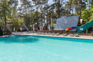 a swimming pool with a slide in a resort at Gryf Domki Pobierowo in Pobierowo