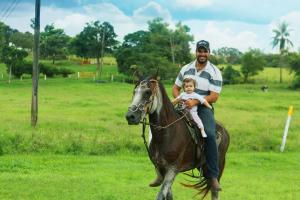 un homme qui fait de l'équitation avec un enfant. dans l'établissement Pousada Portal da Serra, à São João Batista do Glória