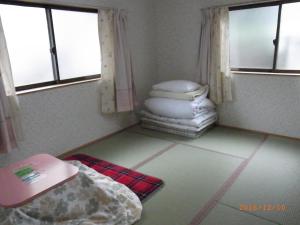 een kamer met een bed en een stapel kussens bij Oyajino Umi in Naoshima