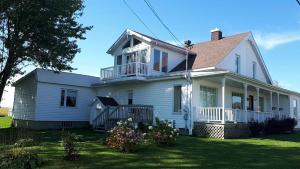 a white house with a balcony on a lawn at Les Gites Makadan in Normandin