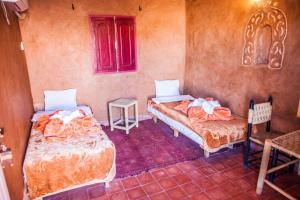 
a bed room with two beds and a table at La Baraka Auberge in Aït Benhaddou
