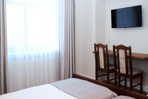 a bedroom with a bed and two chairs and a television at Agropark - Dworek pod Lipą in Sobków