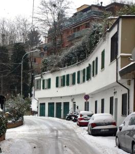 a snow covered street with cars parked in front of a building at charming new loft in Bologna