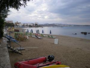 a beach with chairs and umbrellas and the water at Constantinos Studios in Chania