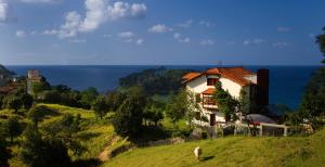 a house on a hill next to the ocean at Hotel Villa Itsaso in Lekeitio