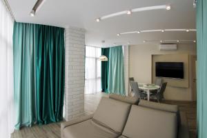 sala de estar con cortinas verdes, sofá y mesa en Апартаменты "Элит" в Олимпийском парке, en Adler