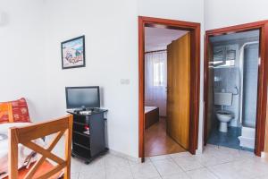 a room with a bathroom with a toilet and a television at Apartmani Maleš in Rogoznica