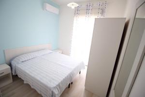 ein weißes Schlafzimmer mit einem Bett und einem Spiegel in der Unterkunft Vista Mare Rivabella in Gallipoli