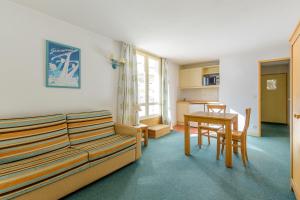 a living room with a couch and a table at Residence Le Montana - maeva Home in La Mongie