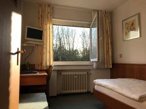 Schlafzimmer mit einem Bett, einem TV und einem Fenster in der Unterkunft Hotel Marienhof Düsseldorf Neuss in Neuss