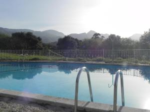 una piscina con dos barras de metal alrededor en Apartamentos Turísticos Las Nieves, en Póo