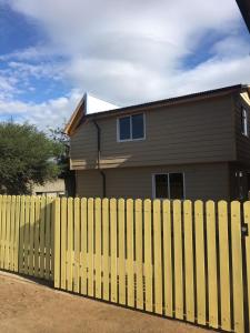 a yellow fence in front of a house at Cabañas Rayen in Río Bueno