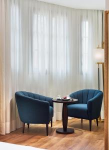 uma sala de estar com duas cadeiras azuis e uma mesa em H10 Madison 4* Sup em Barcelona