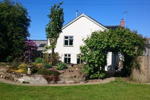 una casa blanca con un jardín delante de ella en Claw House en Holsworthy