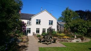 una casa blanca con una mesa de picnic delante de ella en Claw House en Holsworthy