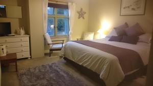 a bedroom with a bed and a dresser and a window at Claw House in Holsworthy