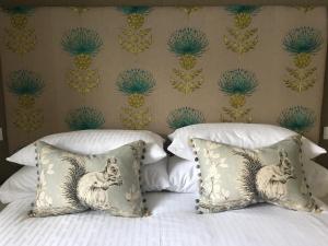 ein Bett mit weißer Bettwäsche und Kissen mit einer Wand in der Unterkunft the house@glenbarr in Glenbarr
