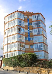un edificio de ladrillo alto con un letrero azul. en Apartamentos Doramar, en Benalmádena