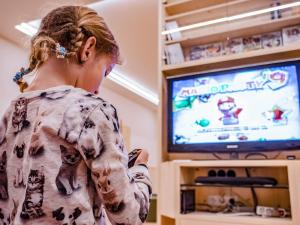 una joven jugando un videojuego en una tele en Luxury and Nature House Moarlhof, en Castelrotto