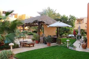 een patio met een parasol en een grasveld bij El Gouna 2 bedrooms apartment South Marina Ground Floor in Hurghada