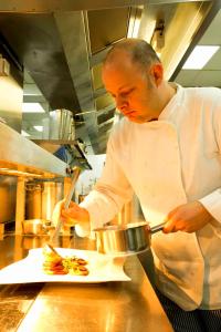 een chef-kok die een bord met eten bereidt in een keuken bij Hotel De Croone in Ninove