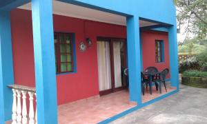 a red and blue house with a table in it at Tri M Waves Lodge in Ponta do Ouro
